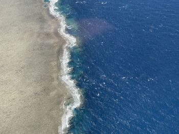 High angle view of sea waves hitting coral reef