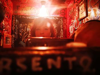 Portrait of woman looking at illuminated shop