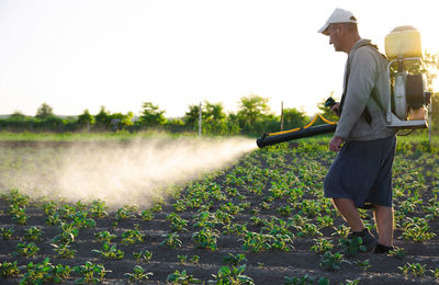 A farmer with a backpack spray treats the plantation with pesticides. protection of plants 