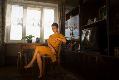 Portrait of young woman sitting on chair at home