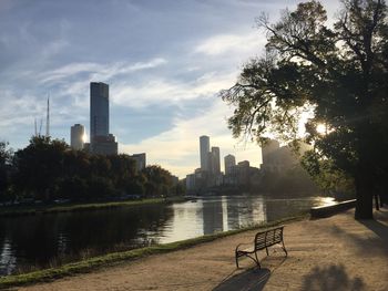 Scenic view of river by city buildings against sky