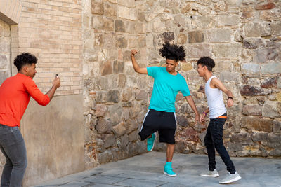 Three afro latin male friends dancing in the street and recording it