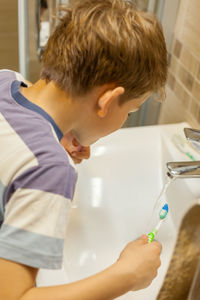 Close-up of boy brushing teeth at bathroom