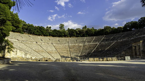 Oldest amphitheater in the world by trees against blue sky