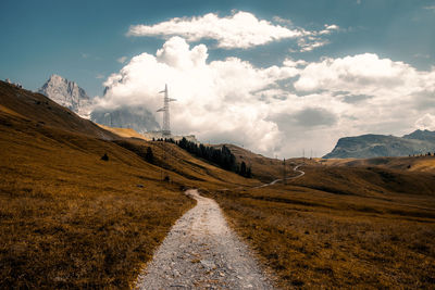 Road amidst field against sky