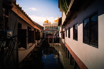 Canal amidst buildings against sky