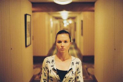 A young woman stands alone in an empty hallway