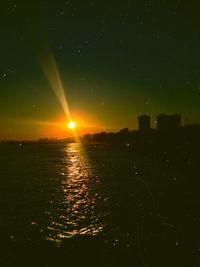 Scenic view of sea against buildings in city at night