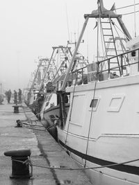 Boats moored at harbor against sky