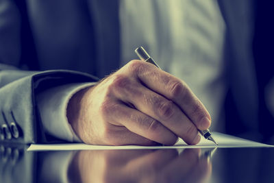 Close-up of hand holding pen on table