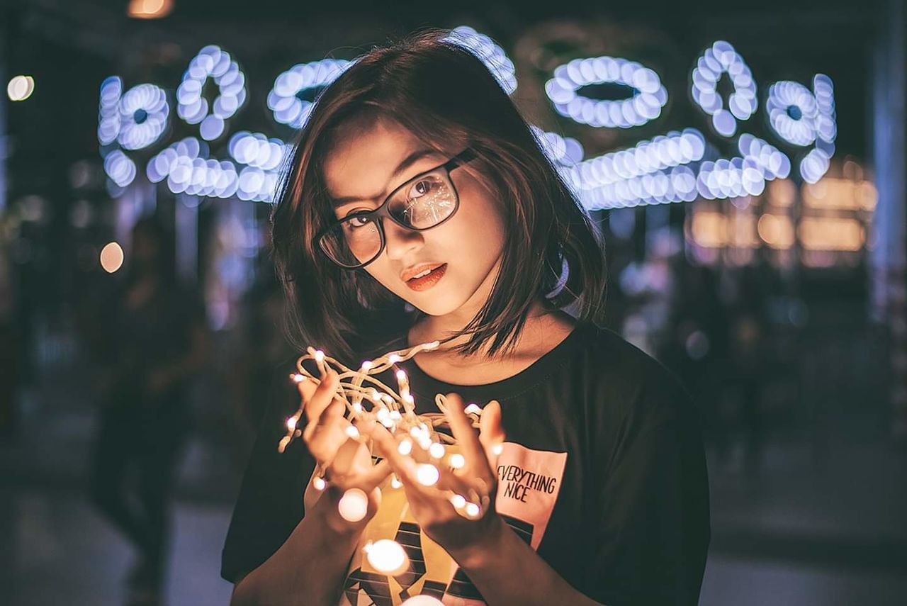 real people, one person, illuminated, front view, portrait, headshot, focus on foreground, leisure activity, lifestyles, holding, glowing, women, night, eyeglasses, child, casual clothing, young adult, girls, outdoors, hairstyle, sparkler