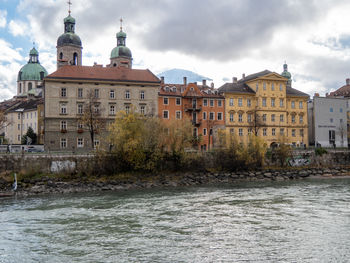 Buildings by river against sky