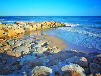 Rocks on beach against clear blue sky