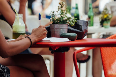 Low section of woman writing on paper  in cafe