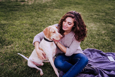 Full length of woman with dog sitting on grass