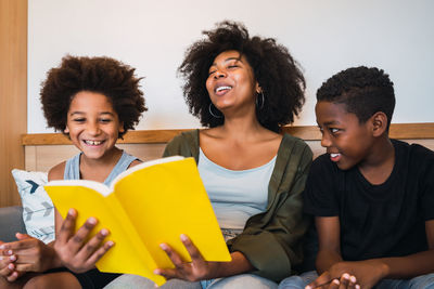 Young woman sitting with boys reading book at home