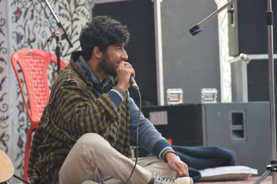 Young man singing while sitting on stage