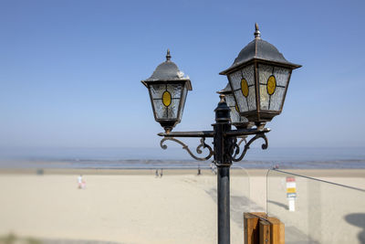 Street light by sea against clear sky