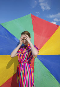 Woman with umbrella standing against the wall