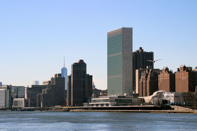 Sea by buildings against clear sky