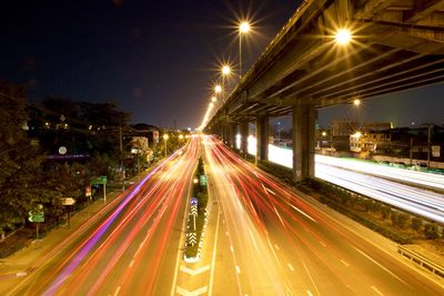 Light trails on road against sky at night