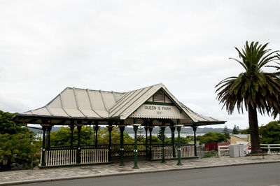 Built structure by palm trees and houses against sky