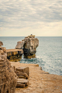 Scenic view of rocks in sea against sky.  pulpit rock on isle of portland in dorset coastline. uk