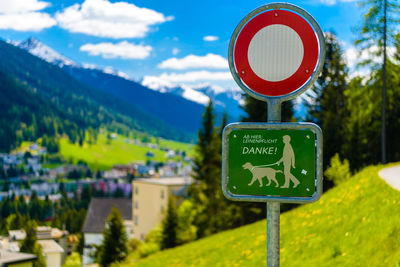 Information sign by road against trees and mountains