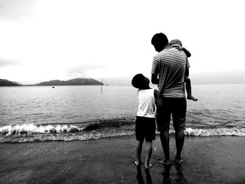 Rear view of father and son walking on beach