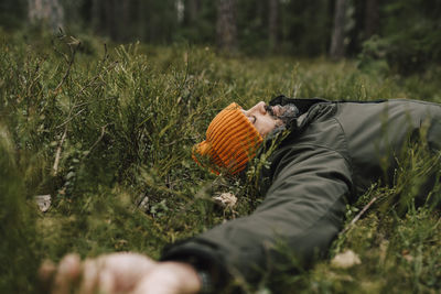 Male explorer resting on grass in forest