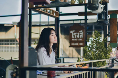 Woman looking away while sitting on window