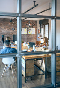 Business people discussing in meeting at office seen through window