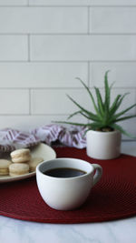 White cup with black coffee served on the table .