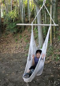 Man sitting on hammock in forest