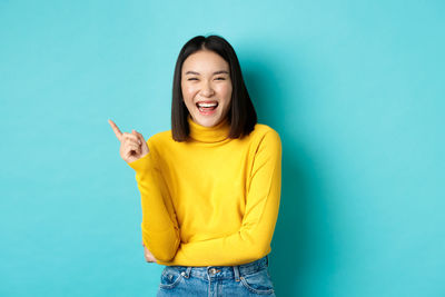 Smiling young woman standing against blue background