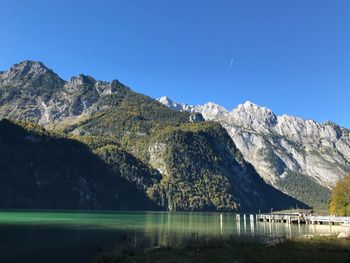 Scenic view of lake and mountains against clear blue sky