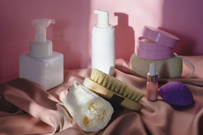 Spa cosmetic products and eco friendly bathroom accessories on a shiny pink fabric background. 