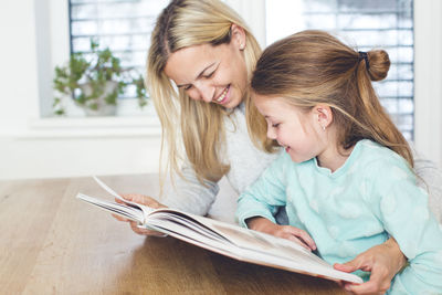 Portrait of mother and daughter holding while sitting at home