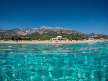 Swimming pool by sea against clear blue sky