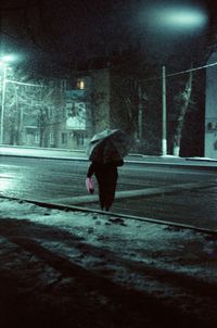 Man walking on wet street at night