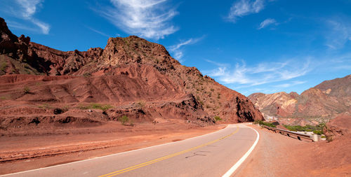 Road leading towards mountains against sky