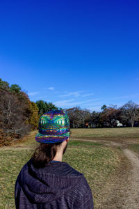 Rear view of woman standing on field against clear blue sky