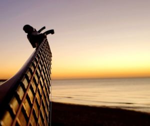 Silhouette man on beach against sky during sunset