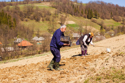 Side view of men working on landscape