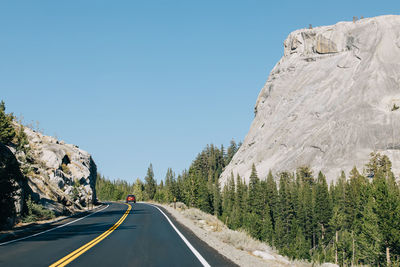 Road amidst rocks against clear blue sky