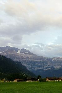 Scenic view of green landscape and mountains against sky