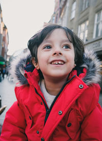 Portrait of cute 4 year old boy wearing red jacket and smiling