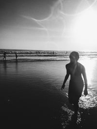 Girl wading in sea against sky