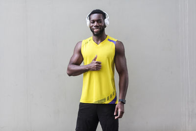 Portrait of young man standing against yellow wall