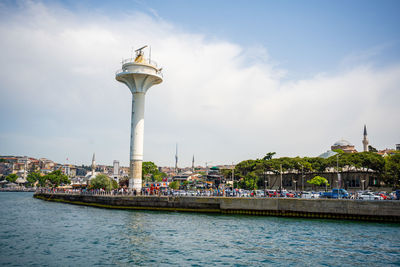 Lighthouse by sea against sky